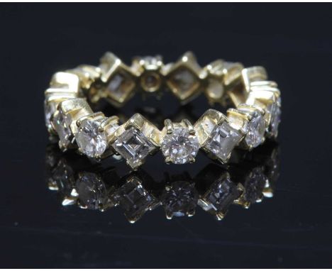 An 18ct gold diamond set full eternity ring, with alternating brilliant cut diamonds and square step cut diamonds, all claw s