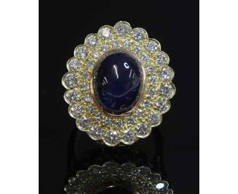 An 18ct gold sapphire and diamond oval cluster ring, with an oval cabochon sapphire, rub set at the centre. A border composed