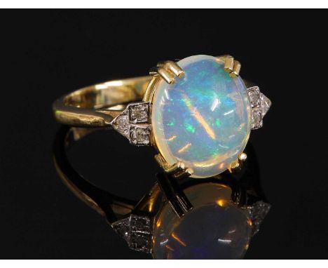 A 9ct gold opal and diamond ring, with an oval cabochon opal, four claw set in a plain collet to the centre. A trefoil cluste