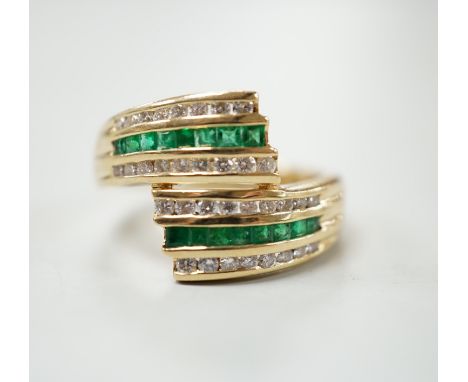 A modern 14k yellow metal, emerald and diamond chip set triple row crossover ring, size O, gross weight 5.4 grams.