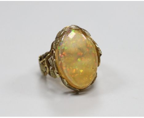 A yellow metal and oval jelly? opal set dress ring, with rustic foliate shank and setting, size L, gross weight 8.6 grams.