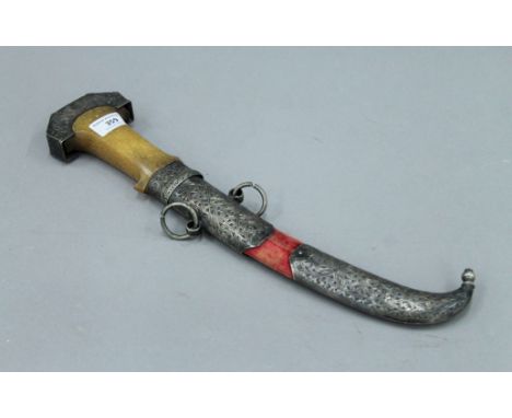 An antique jambiya, the handle possibly rhino horn and with unmarked white metal mounted scabbard, the blade with gilt decora