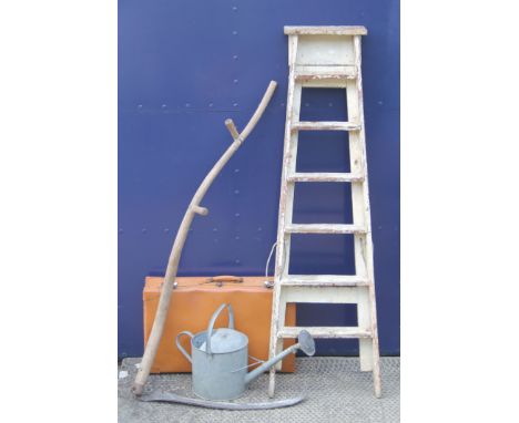 A vintage painted step ladder, a watering can, a scythe and a vintage suitcase.