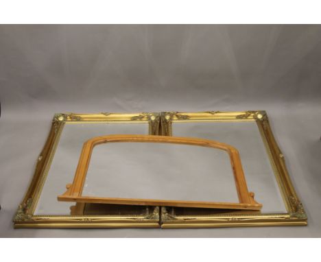 Two modern gilt framed mirrors and a pine over mantle mirror. The former each 105 x 75 cm.