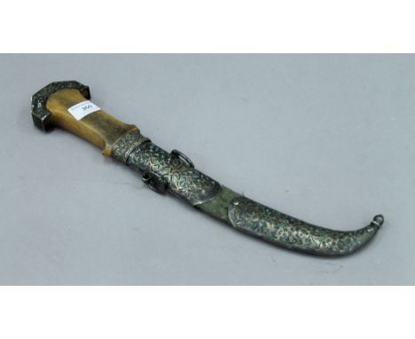 An antique jambiya, the handle possibly rhino horn and with unmarked white metal mounted scabbard, the blade with gilt decora