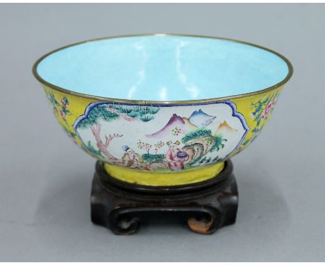 A late 19th/early 20th century Canton yellow ground enamel bowl on a wooden stand. 17 cm diameter.