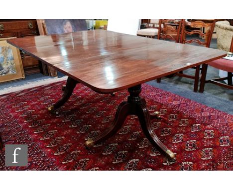 A 19th Century mahogany twin pedestal extending dining table with central leaf, rounded ends on turned pedestal splayed tripo