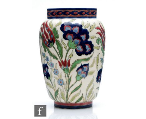 A Zsolnay Pecs barrel vase decorated in the Persian style with tulip and carnations in tones of red and blue against a pale g