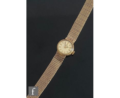 A 9ct hallmarked Omega, manual wind wrist watch, gilt batons to a circular dial, case diameter 18mm, to an integral 9ct brace