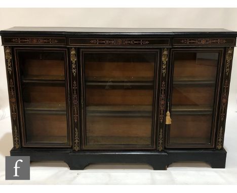 A Victorian gilt metal mounted and ebonised breakfront credenza, the shelf interior enclosed by three glazed doors, on a brac