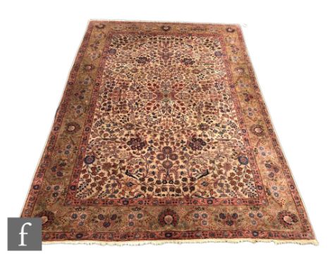 A Heriz style carpet, the central ivory ground set within green and rich salmon pink borders, detailed with arabesque style m