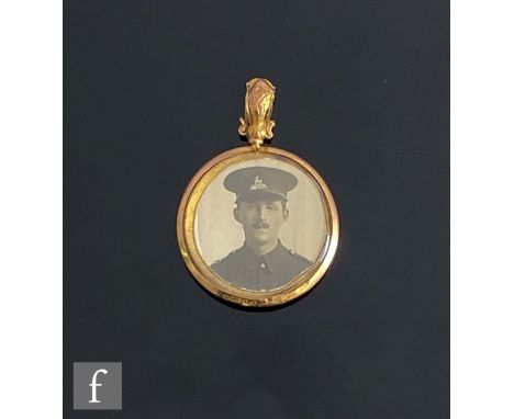 An early 20th Century open circular open locket with a photograph of a soldier to one side and an enamel Birmingham Battalion