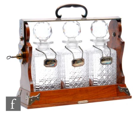 A Betjemann’s patent walnut three bottle tantalus with plated mounts, fitted with three whisky decanters and plated labels Br