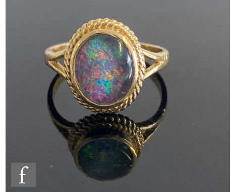 A 9ct hallmarked oval opal doublet single stone ring, collar set within a rope twist border and split shoulders, weight 3.1g,