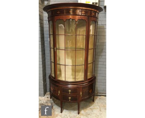 An Edwardian mahogany display cabinet of demi-lune outline, the cornice pediment with line inlaid foliate detail above a bar 