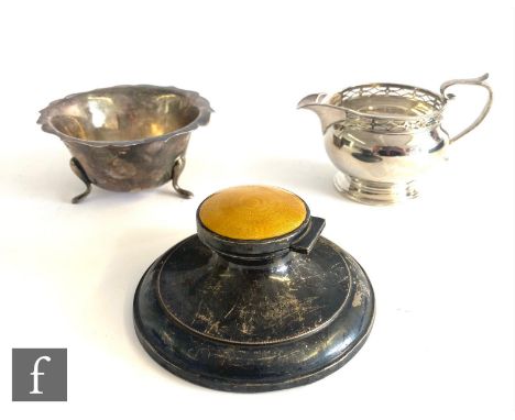 Three items of hallmarked silver, a cream jug, a sugar basin and a capstan ink well with yellow enamel detail to hinged cover