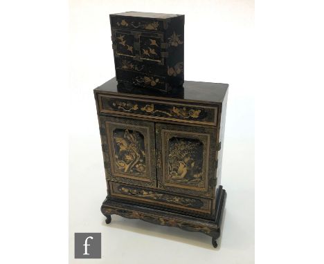 A late 19th Century Japanese black chinoiserie lacquered table cabinet on stand, the centre section with a pair of doors and 