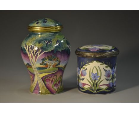 A Moorcroft  enamel cylindrical pot and cover, with cornflowers,  4.5cm high, boxed;  another, baluster, with tall trees and 