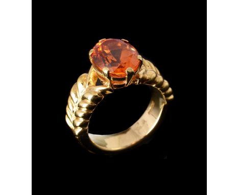 GRATIA SCOTT-OLDFIELD, AN 18 CARAT GOLD SPESSARTINE GARNET DRESS RINGthe oval cut garnet in six claw setting to bifurcated lo