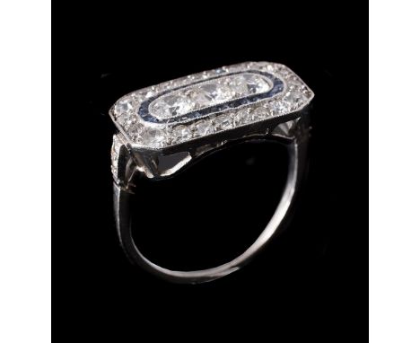AN ART DECO DIAMOND AND SAPPHIRE PANEL RING, CIRCA 1930the rectangular panel with canted corners centrally set with a trio of