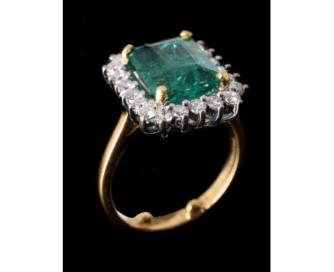 AN EMERALD AND DIAMOND CLUSTER RINGthe step cut emerald with canted corners, estimated to weigh 3.41 carats, within a surroun
