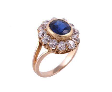 A SAPPHIRE AND DIAMOND CLUSTER RINGthe central cushion shaped sapphire estimated to weight 1.93 carats in a collet setting, w