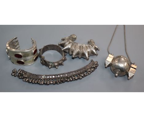 Two Eastern white metal open bangles, a bracelet with bells, one other hinge bangle and a pill? box pendant.