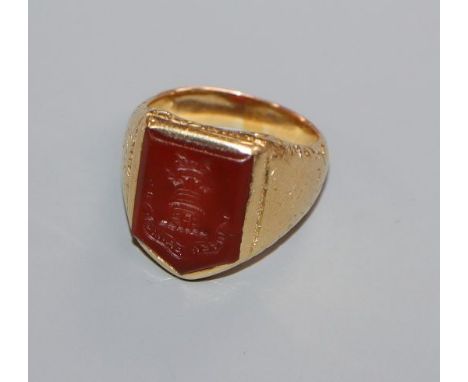 A 19th century yellow metal and carnelian set signet ring, the matrix carved with castle turret and motto, size J/K.