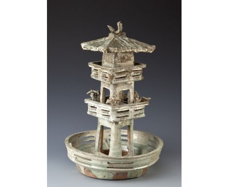 A CHINESE GLAZED POTTERY MODEL OF A TWO STOREY WATCHTOWER HAN DYNASTY With a sloping roof with a bird surmount and figures of