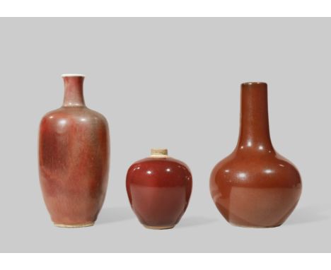 THREE SMALL CHINESE RED GLAZED VASES QING DYNASTY One an ovoid vase with a cylindrical neck and a six character Kangxi mark, 