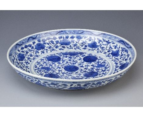 A LARGE CHINESE BLUE AND WHITE SAUCER DISH KANGXI 1662-1722 Painted with stylised lotus flowerheads and scrolling leaves enci