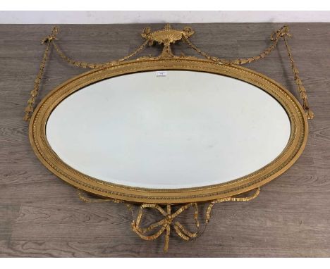 EDWARDIAN GILT FRAMED WALL MIRROR, of neoclassical design, with a central urn finial flanked by husk festoons and ribbon over