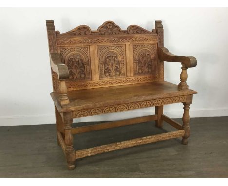 CARVED OAK SETTLE, EARLY 20TH CENTURY  with carved foliate detail and swept arms, raised on turned baluster supports  107cm w