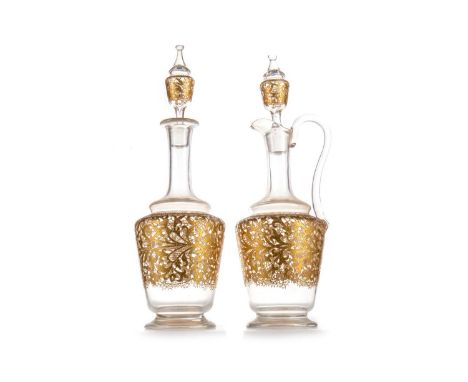 TWO VICTORIAN GLASS DECANTERS WITH STOPPERS, LATE 19TH CENTURY  one with a loop handle, both decorated in gilt enamel38cm hig