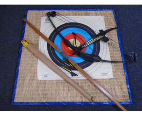 An archery target together with two bows, arrows and a crossbow with bolts.