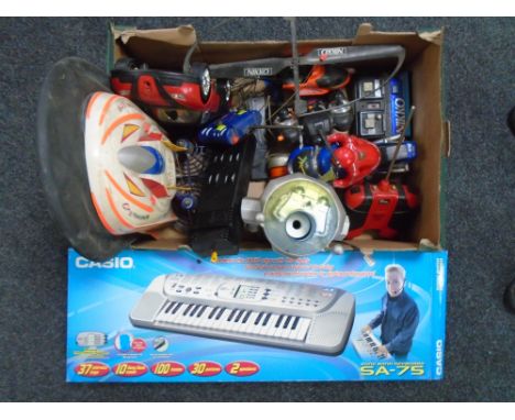 A box containing a quantity of assorted remote control cars together with a Casio SA-75 keyboard.