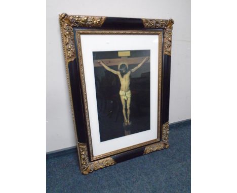 A colour print depicting the crucifixion of Christ in an ornate black and gilt frame.