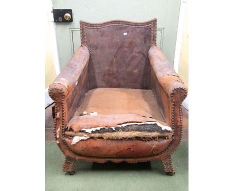 An Edwardian library/lounge chair with original leather upholstered finish (poor), the framework with steel button borders an