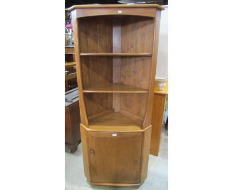 An Ercol blonde elm freestanding corner cupboard the lower section enclosed by a rectangular door with dished handle beneath 