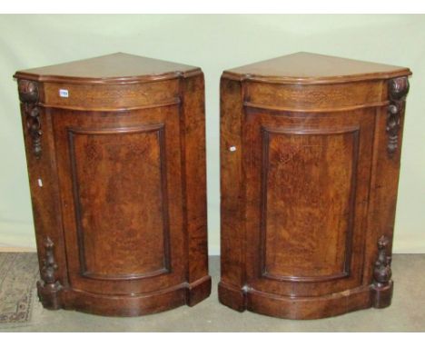 A pair of Victorian burr and figured walnut veneered floorstanding bow fronted corner cupboards, each enclosed by a rectangul