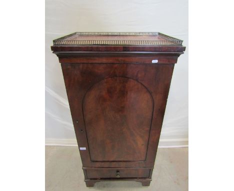 A 19th century mahogany pedestal cupboard with raised pierced brass gallery over and enclosed by arched panelled door with fu