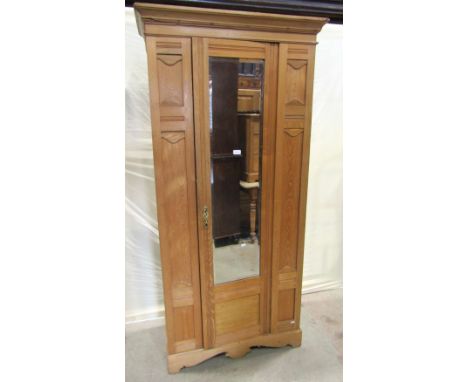 An Edwardian ashwood single wardrobe enclosed by a full length central door with bevelled edge mirror plate, flanked by mould