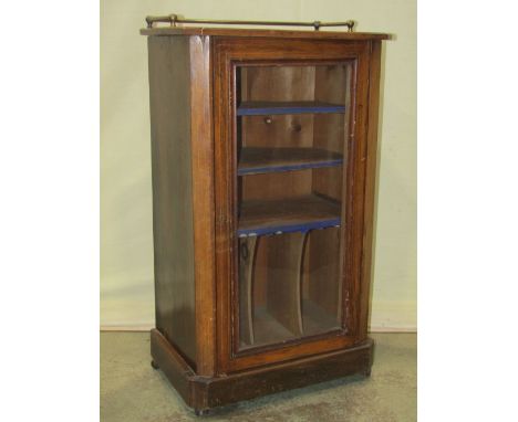 A Victorian walnut music cabinet enclosed by a rectangular glazed panelled door revealing a shelved interior flanked by cante