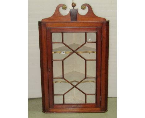 A 19th century mahogany hanging corner cabinet enclosed by an astragal glazed panel door, revealing two fixed shaped shelves 