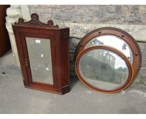 An Edwardian walnut hanging corner cupboard enclosed by a rectangular mirror panelled door flanked by carved flower head deta