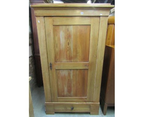 A European stripped pine knockdown single wardrobe, enclosed by a twin panelled door, over a long drawer to base, easily dism