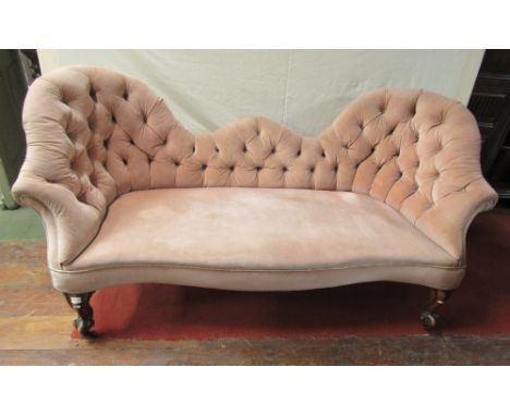 A Victorian sofa with shaped outline, upholstered finish, button back and scrolled cabriole forelegs
