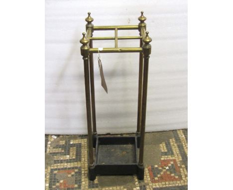 A brass four divisional umbrella/stick stand, with tubular rails, turned finials and cast iron drip tray