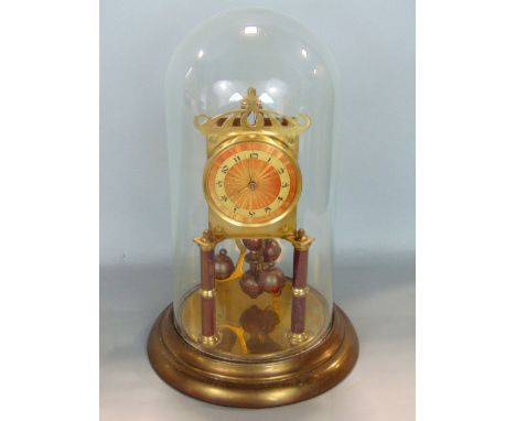 Brass 400 day anniversary clock under a glass dome, with orange sunburst dial and brass chapter ring and Arabic numerals upon