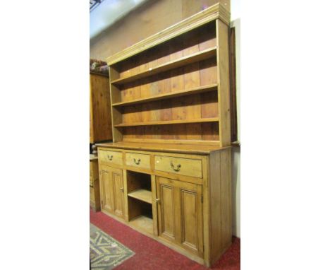 A vintage stripped pine kitchen dresser, the base enclosed by a pair of twin moulded rectangular panelled doors, flanking a c